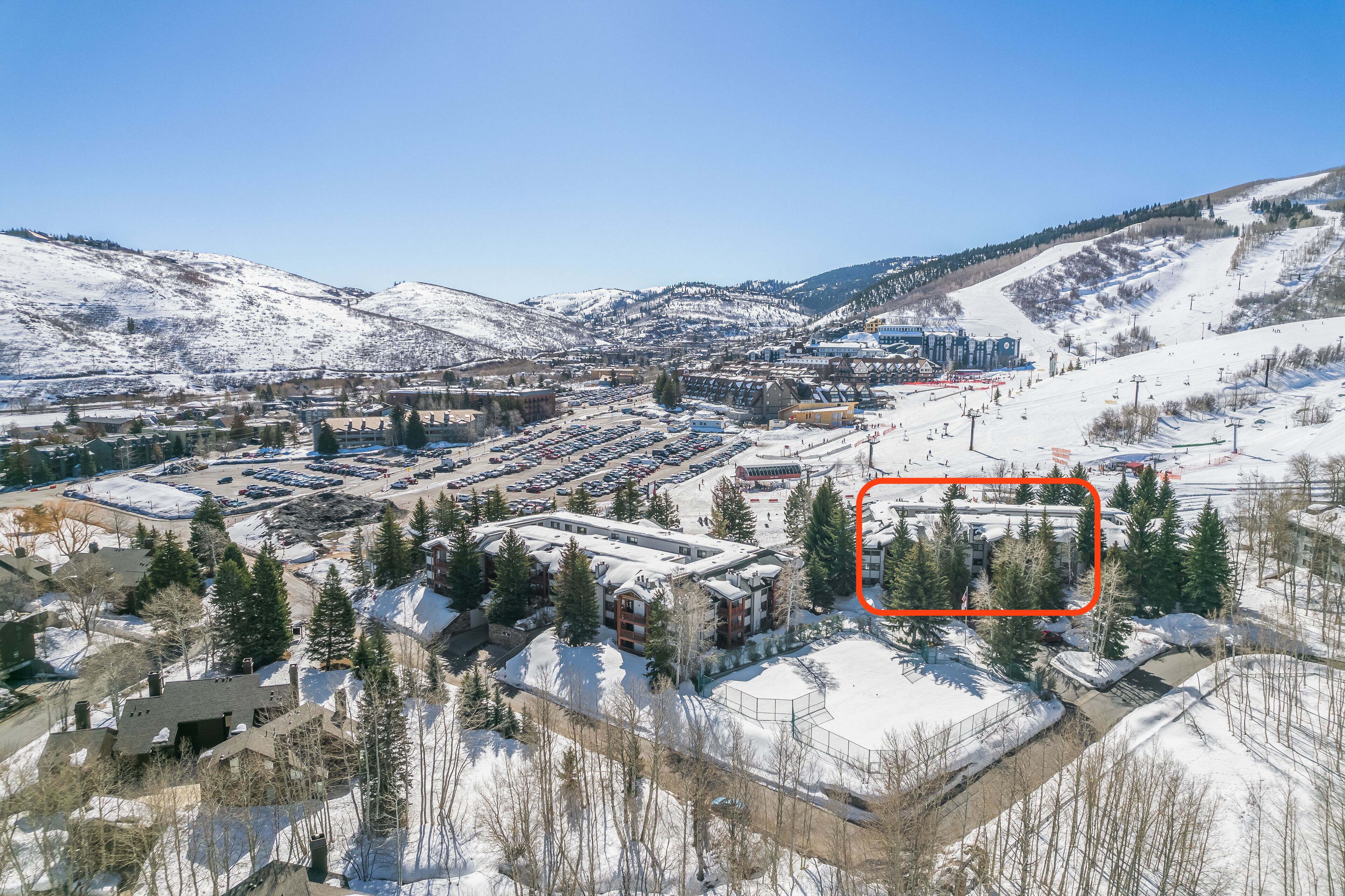 Une station de ski enneigée comprenant plusieurs bâtiments, des aires de stationnement et des remontées mécaniques.