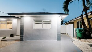 A modern house with a garage, a driveway, and a palm tree. - Adorable Studio (Miami)