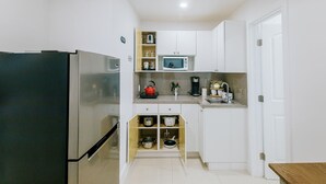 A compact kitchen with white cabinets, a stainless steel refrigerator, a microwave, and a coffee maker. - Adorable Studio (Miami)