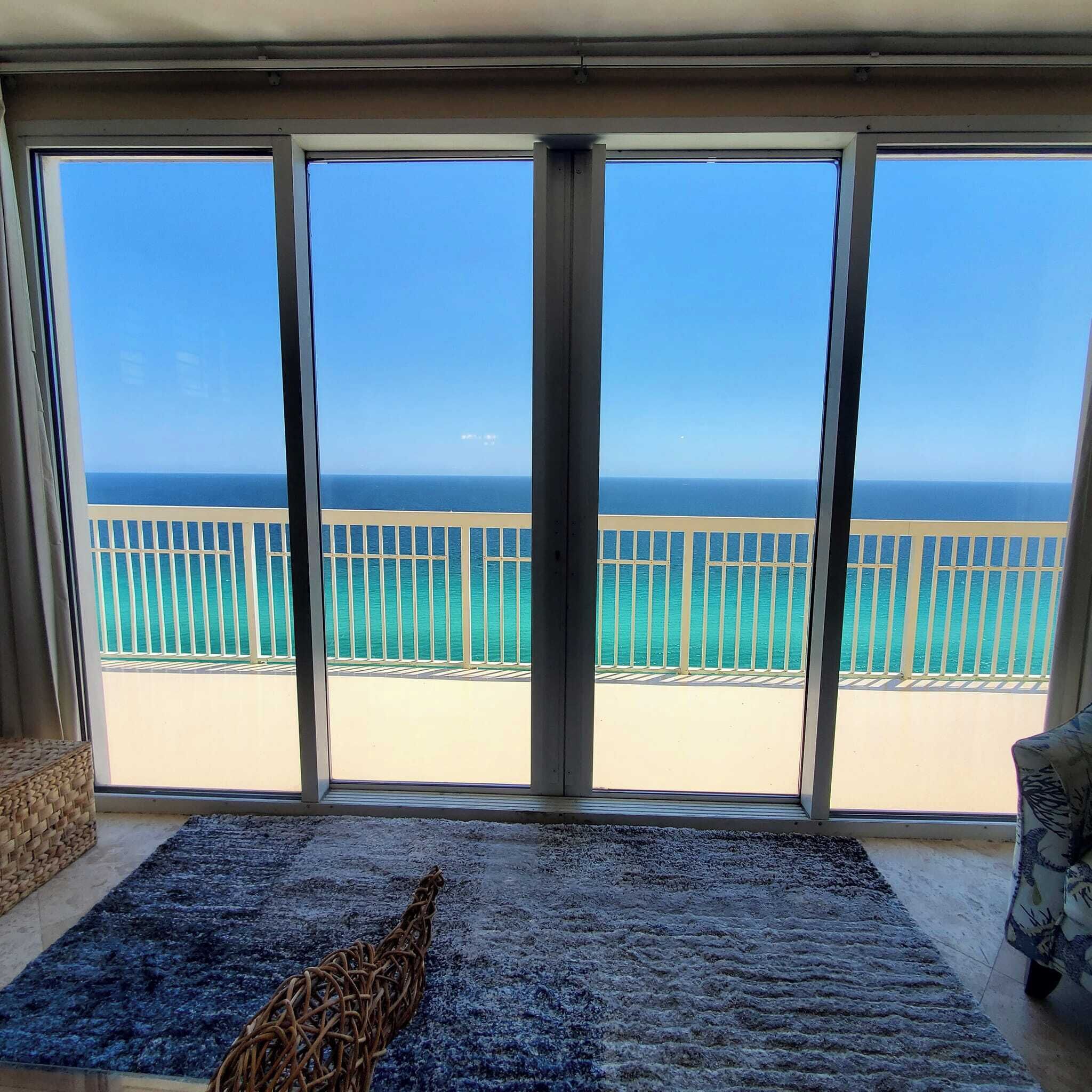 Et værelse med stor skydedør til en balkon med havudsigt og en sandstrand.