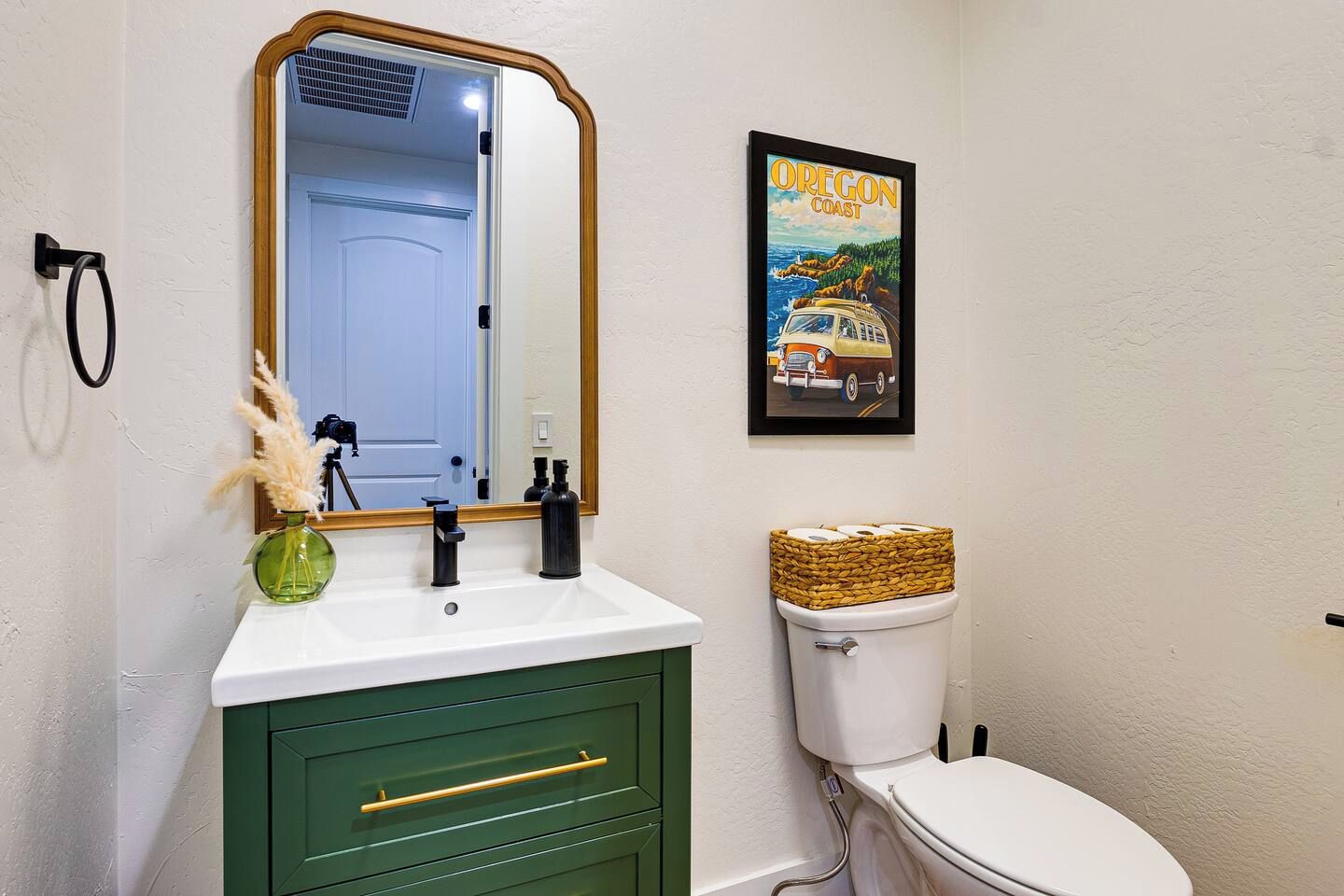 A bathroom with a white toilet, green cabinet, and a mirror with a wooden frame.