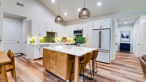 A modern kitchen with white cabinets, a central island, and a microwave.
