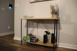 Une console en bois dotée d’une étagère, sur laquelle sont posés des livres, un haut-parleur et un objet décoratif.