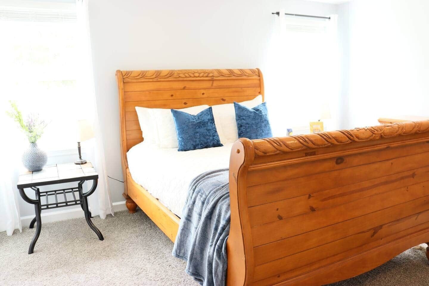 A bedroom with a wooden bed, a bedside table, and a window with curtains.