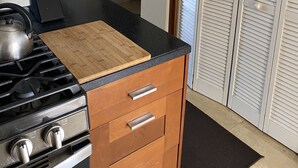 Une cuisine équipée d’une cuisinière, d’une planche à découper et de meubles de rangement en bois.