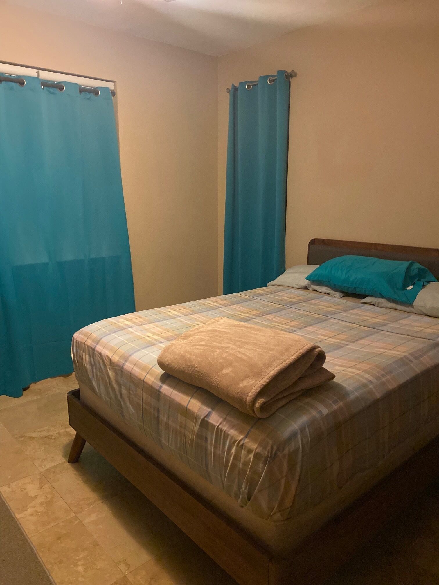 A bedroom with a bed, curtains, and a headboard.