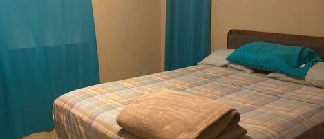 A bedroom with a bed, curtains, and a headboard.