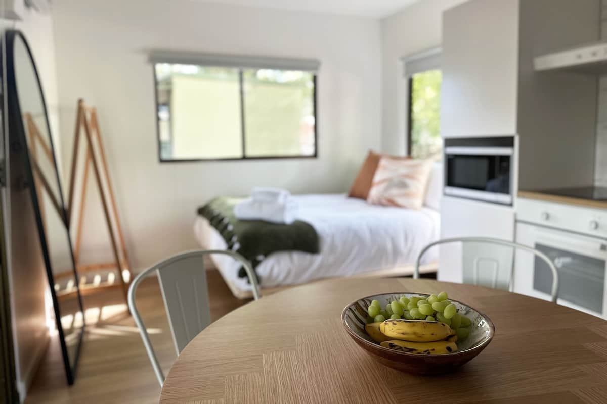 Quarto moderno com cama, janela e área de cozinha.