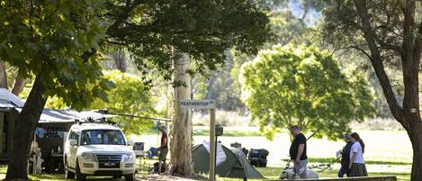 Un campamento con tiendas de campaña, un coche aparcado y un cartel que dice 'FEATHERTOP DR'.