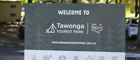 A welcome sign for Tawonga Tourist Park with camping, RV, and BBQ symbols.