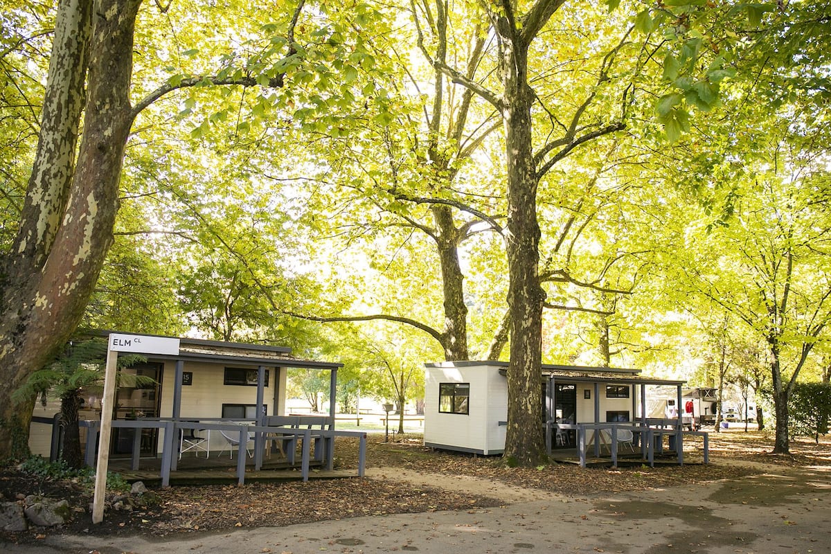 Um camping com duas cabanas pequenas, cada uma com varanda e mesa.