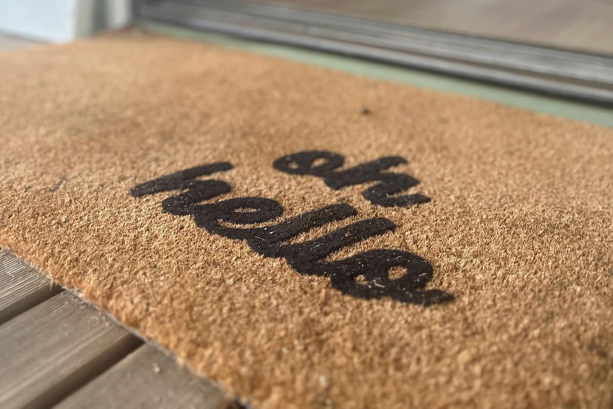Um close-up de um tapete de entrada com as palavras 'hello' e 'welcome'.