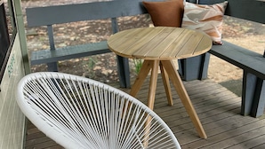 A covered outdoor seating area with a wooden table and a white chair. - Tawonga Tourist Park (Tawonga)