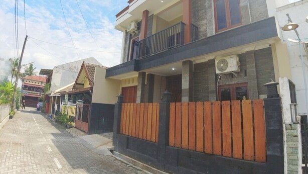 A two-story residential building with a balcony, air conditioning units, and a wooden fence. - Eltanin Homestay by FH Stay (Depok)