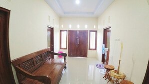 A hallway with a wooden bench, a small round table, and a door at the end. - Eltanin Homestay by FH Stay (Depok)