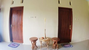 A room with two wooden doors, a small round table with a vase, and two stools. - Eltanin Homestay by FH Stay (Depok)