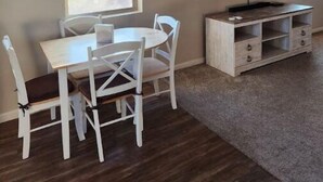 Un coin repas comprenant une table et des chaises, un téléviseur et un meuble.
