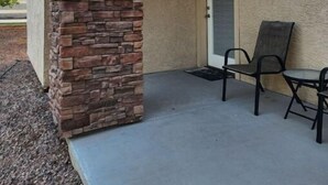 Un bâtiment doté d’une façade en pierre, d’une porte et d’un petit patio avec une table et des chaises.