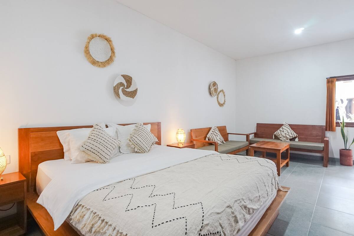 Une chambre bien rangée, avec un lit en bois, un banc en bois et une petite table.