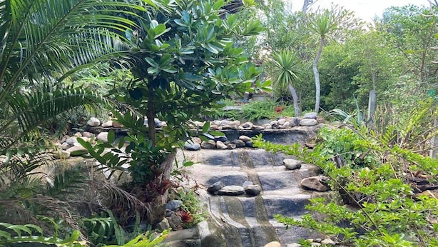 A natural rock formation with a cascading water feature surrounded by lush greenery. - Nokkamin Home Chiang Dao  (Chiang Dao)