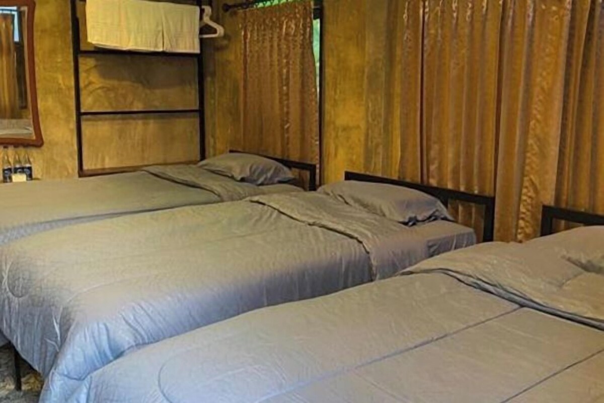 A room with two single beds, wooden walls, and a hanging light fixture.