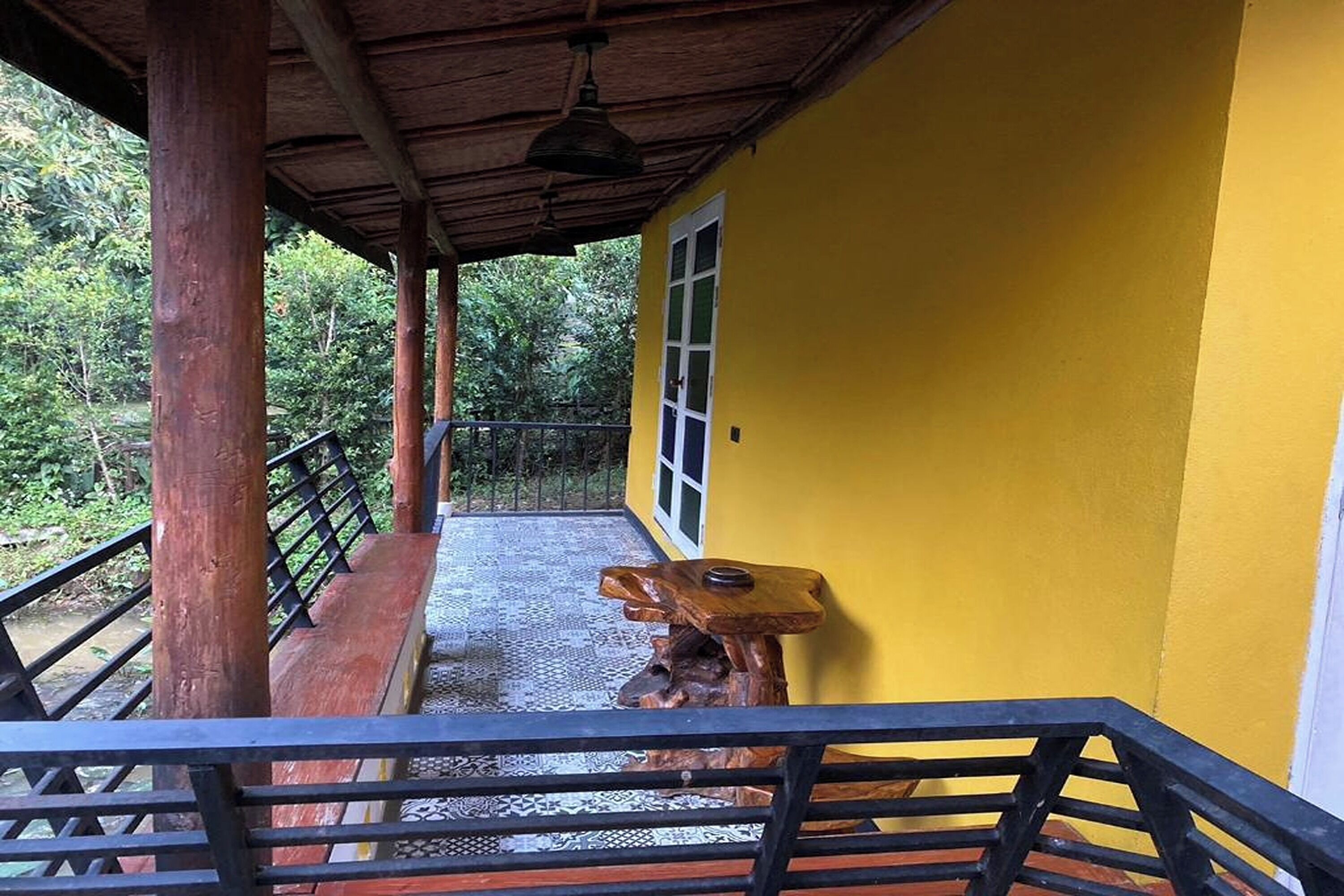 A wooden staircase leading to a yellow building with a window and a decorative wooden sculpture.
