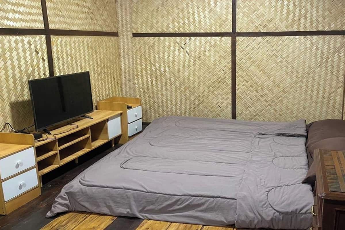 A room with a bed, a TV on a wooden stand, and a small wooden table.