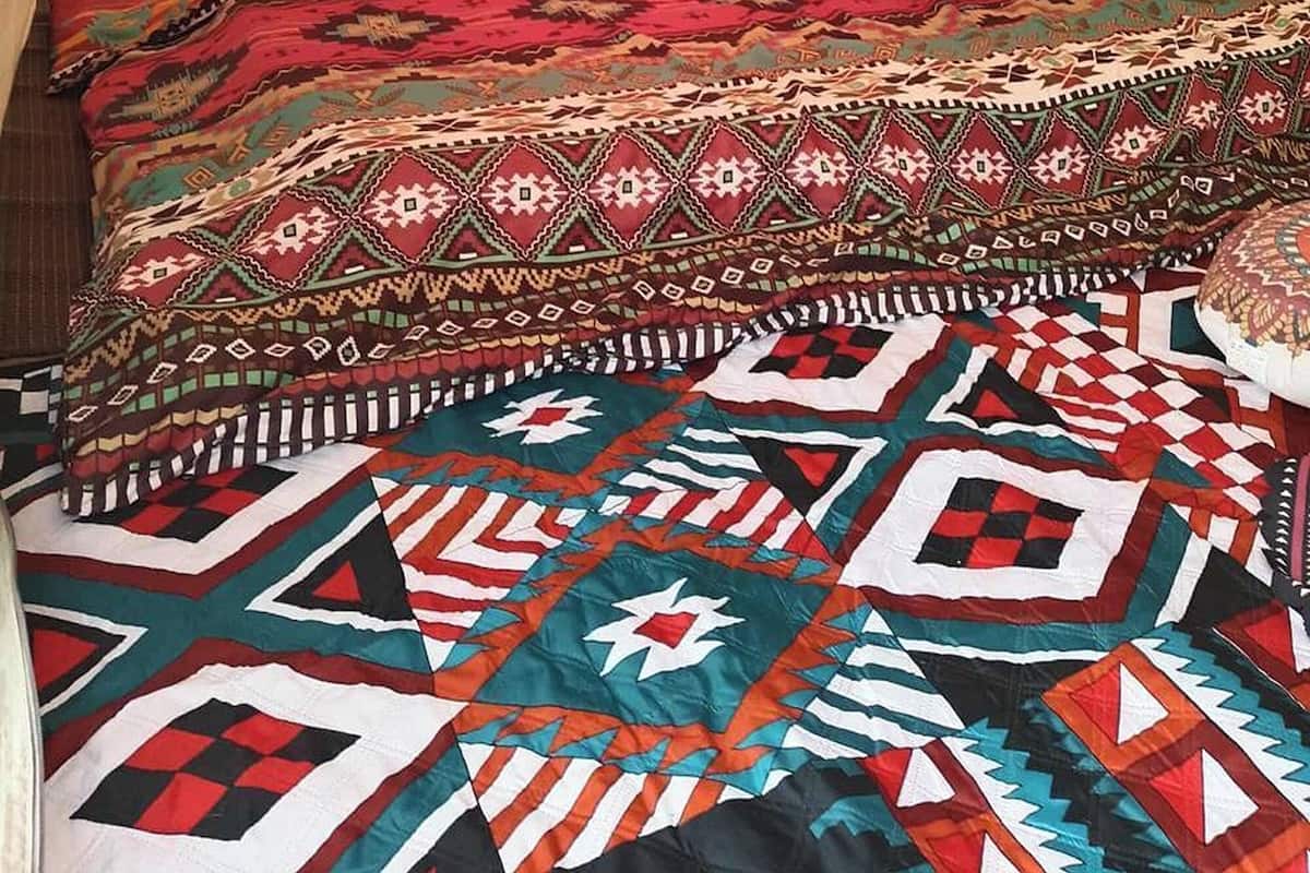 A tent with a bed inside, featuring a patterned blanket and pillows.