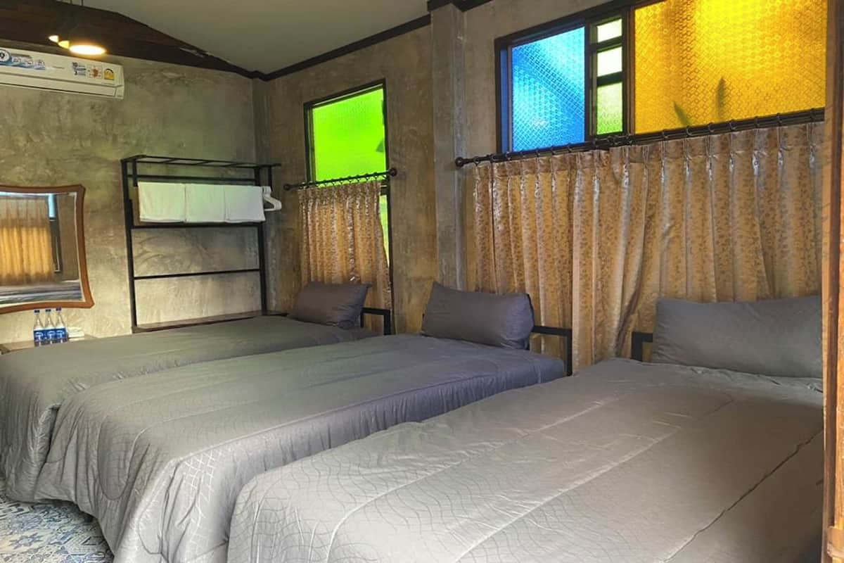 A room with two beds, a bunk bed, and a window with curtains.
