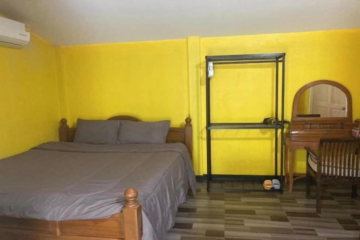 Una habitación con una cama, un escritorio con espejo y una silla.