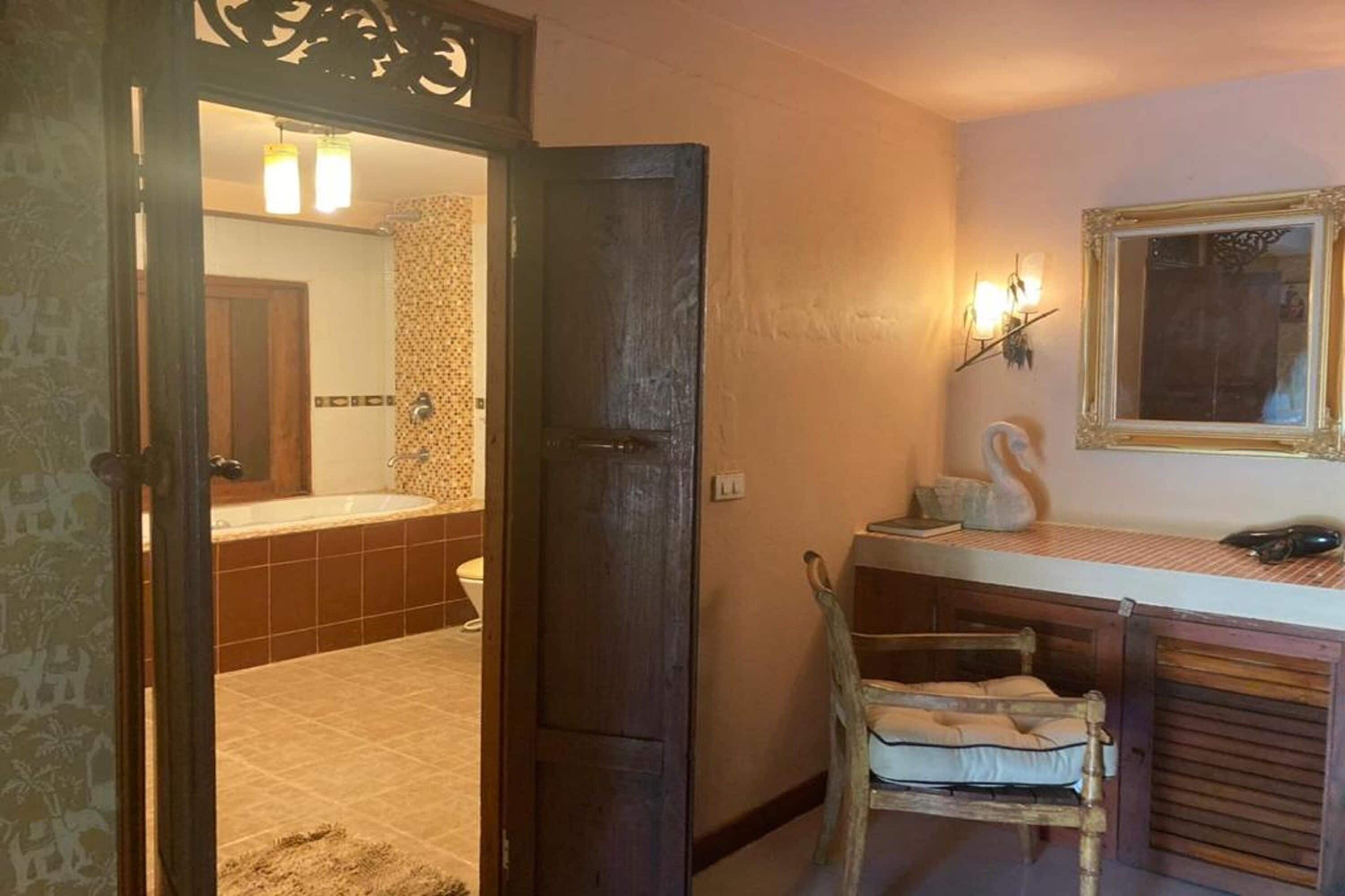 A bathroom with a bathtub, a toilet, and a sink. There is a mirror above the sink and a decorative wall piece.