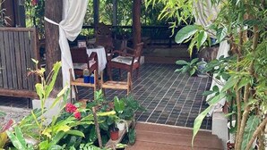 A covered outdoor area with wooden flooring, potted plants, and a table with chairs. - Nokkamin Home Chiang Dao  (Chiang Dao)