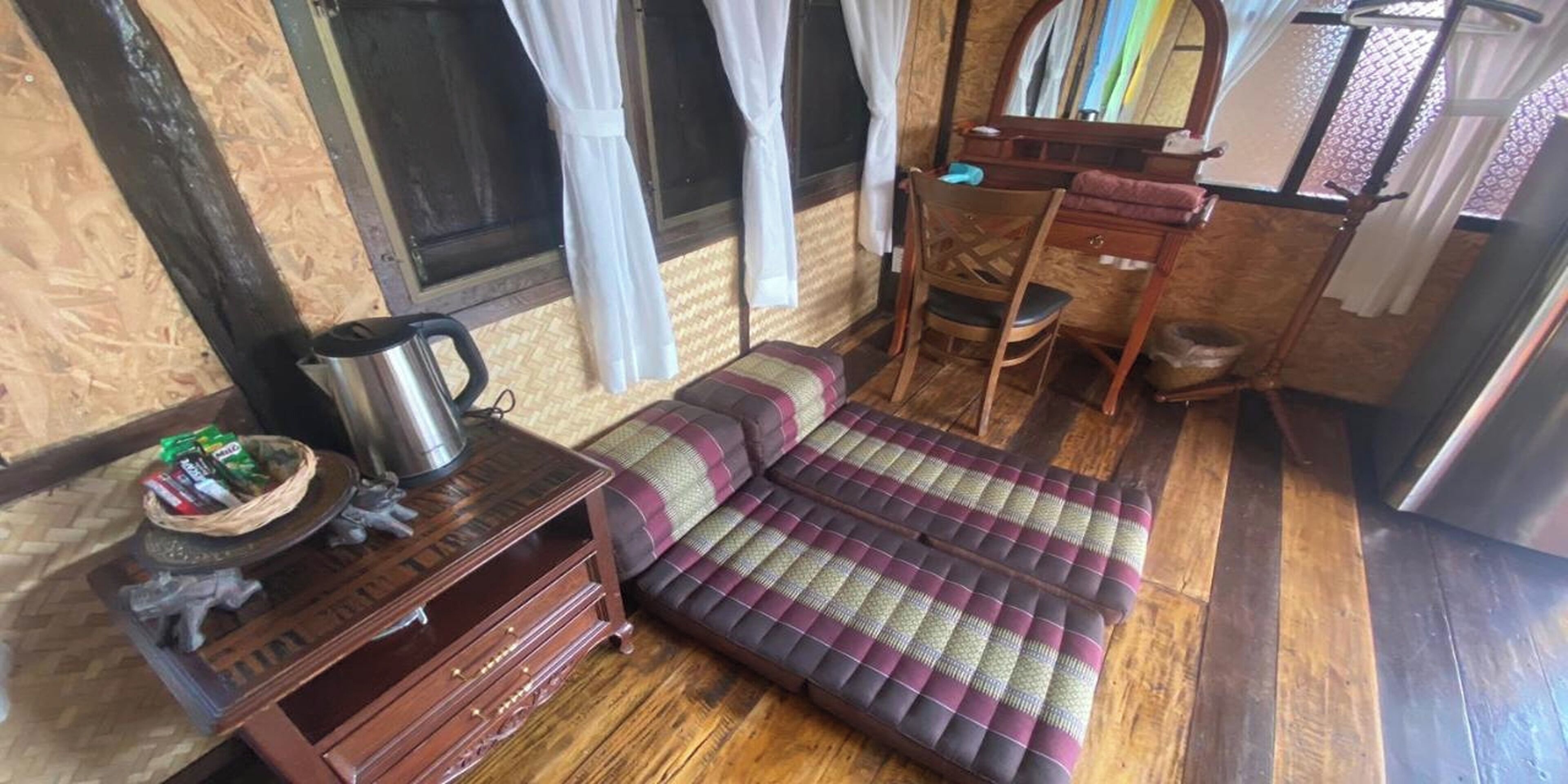 A room with a sofa, a wooden cabinet, a mirror, and a window with curtains.