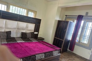 A bedroom with a bed, a wardrobe, and a window with curtains. - N V Villa Homestay (Kasauli)