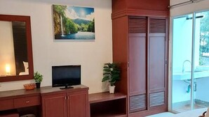 Ein Schlafzimmer mit Bett, Fernseher, Schreibtisch und Kleiderschrank.