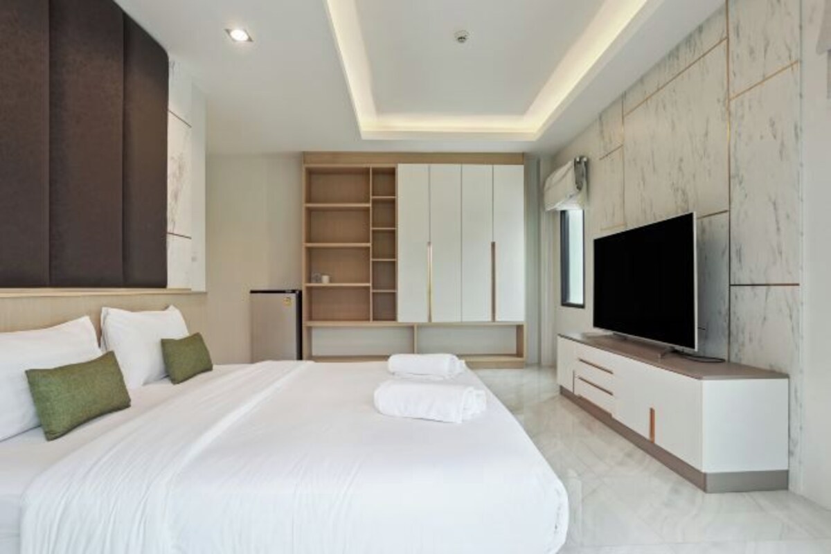 A modern hotel room with a large bed, built-in wardrobe, and a flat-screen TV.