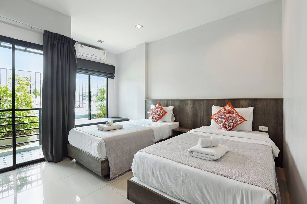 Een hotelkamer met twee bedden, een groot raam en een airconditioning.