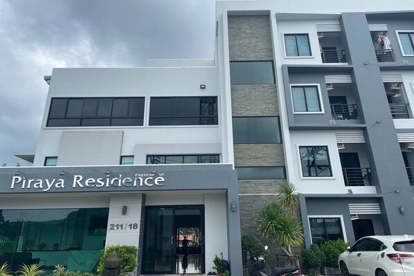 Un immeuble moderne portant l’enseigne « Piraya Residence » et dont l’adresse, « 211/18 », est clairement visible.