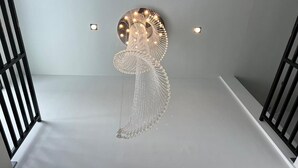 A modern interior with a unique wall art piece featuring a circular design with hanging elements. - De Piraya Residence (Mai Khao)
