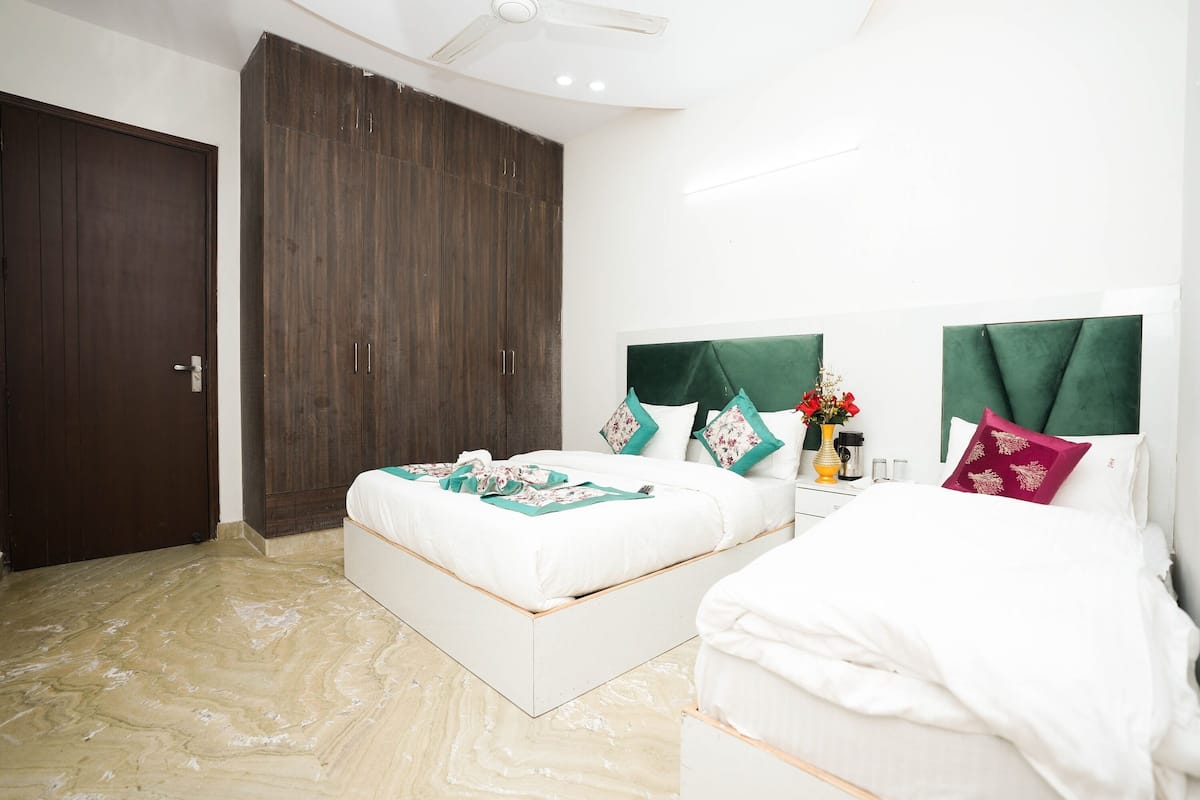 A bedroom with two beds, a dark wooden wardrobe, and a white ceiling fan.