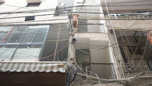 A multi-story building with visible electrical wiring and a metal railing on the balcony. - Sarthi Home Stay (New Delhi)