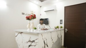 A reception desk with a marble design, a dark wooden door, and a wall-mounted air conditioning unit. - Sarthi Home Stay (New Delhi)