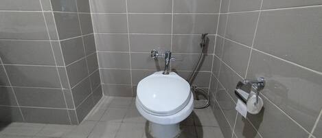A small, modern bathroom with a white toilet, a shower, and a towel rack.