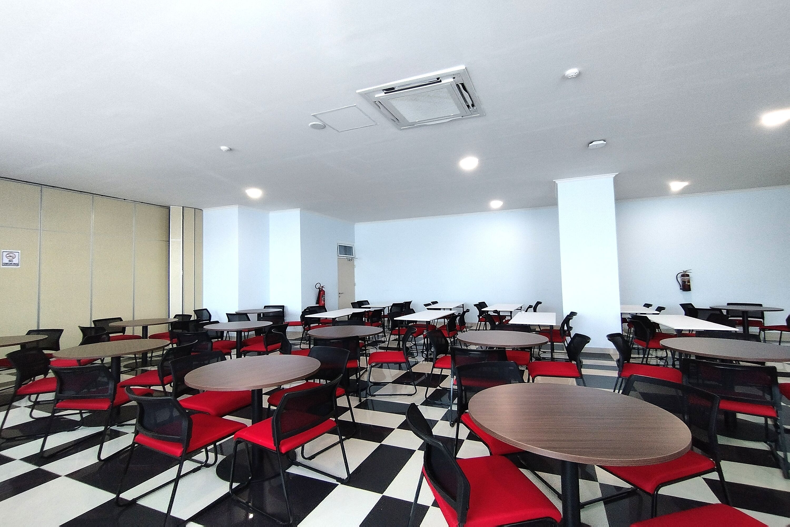 A conference room with multiple tables and chairs, a checkered floor, and ceiling lights.
