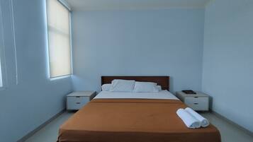 A bedroom with a bed, two nightstands, a window, and a brown bedspread.