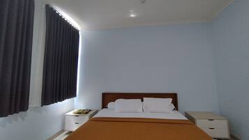 A bedroom with a single bed, white bedding, a brown throw blanket, and two bedside tables with lamps.