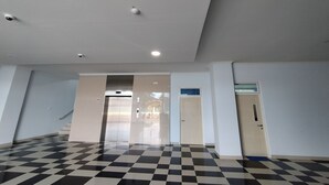 A spacious hallway with a checkered floor, a door on the right, and a staircase in the background. - Hotel Sutha Inn Syariah (Jambi)