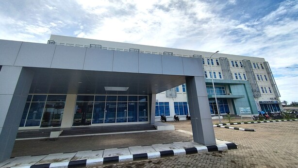 A modern building with large windows and a covered entrance area. - Hotel Sutha Inn Syariah (Jambi)