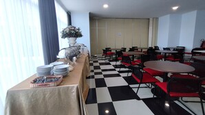A dining area with checkered flooring, tables, and chairs. - Hotel Sutha Inn Syariah (Jambi)