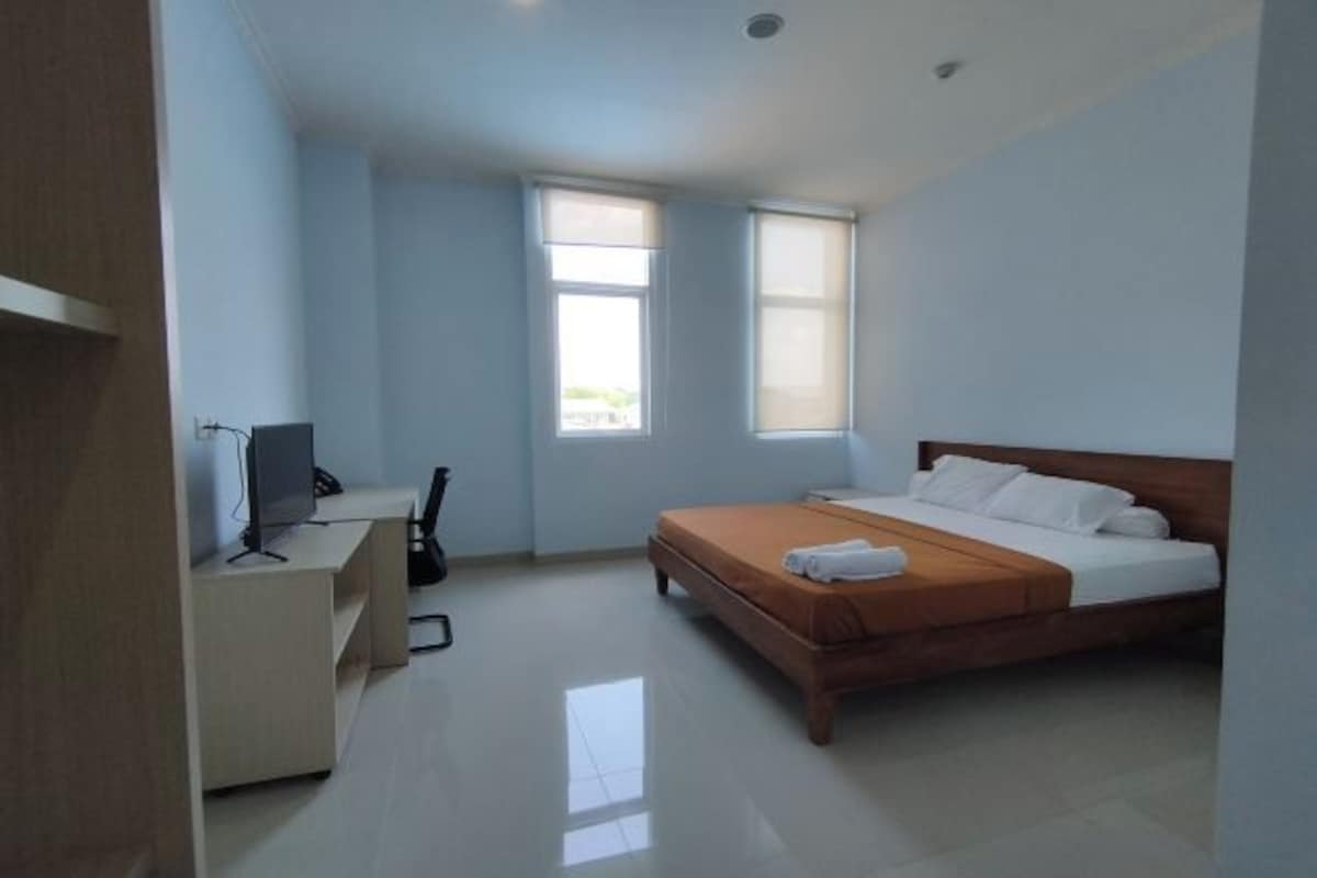 Un dormitorio con cama, escritorio, silla y ventana.